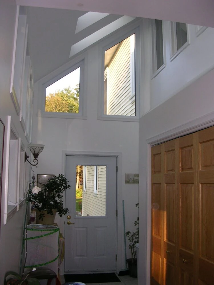 A Hallway Featuring a Door and Several Windows, Illuminated by Natural Light Streaming Through the Glass.